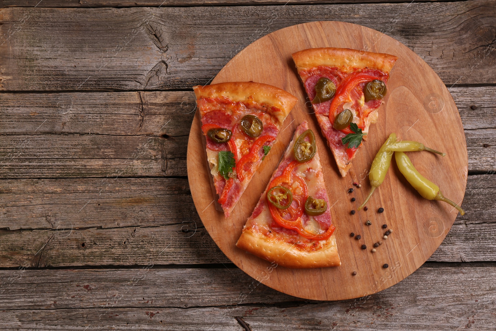 Photo of Pieces of delicious pizza Diablo, pickled peppers and spices on wooden table, top view. Space for text