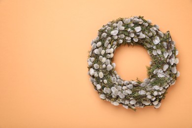 Wreath made of beautiful willow flowers on orange background, top view. Space for text