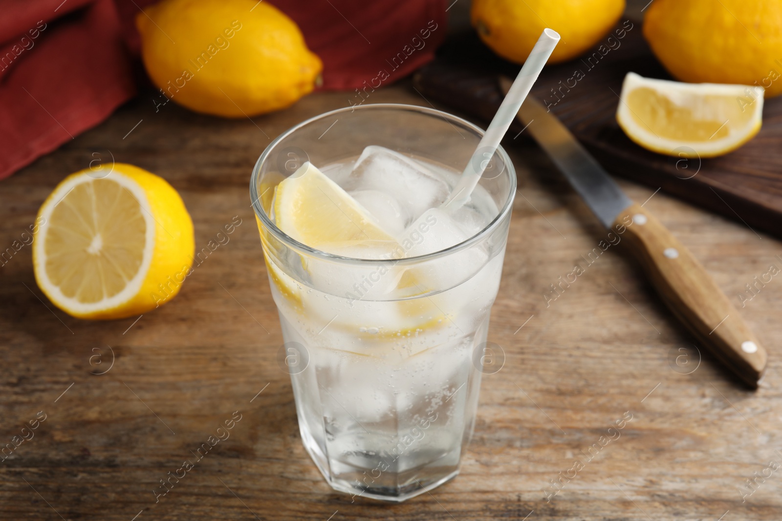 Photo of Soda water with lemon slices and ice cubes on wooden table