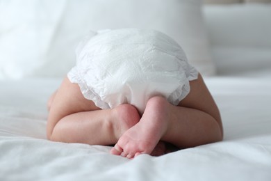 Cute little baby in diaper on bed