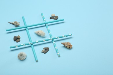 Photo of Tic tac toe game made with sea treasures on light blue background