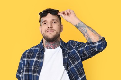 Photo of Portraithandsome hipster man with stylish sunglasses on yellow background