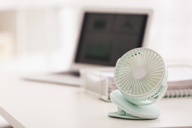 Photo of Modern electric fan on table in office. Space for text