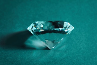 Photo of Beautiful dazzling diamond on green textured background, closeup