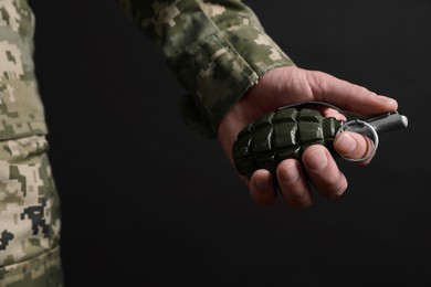 Photo of Soldier holding hand grenade on black background, closeup. Military service