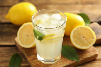 Cool freshly made lemonade in glass on wooden table, closeup