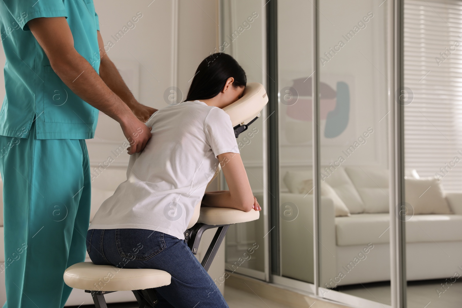 Photo of Woman receiving massage in modern chair indoors