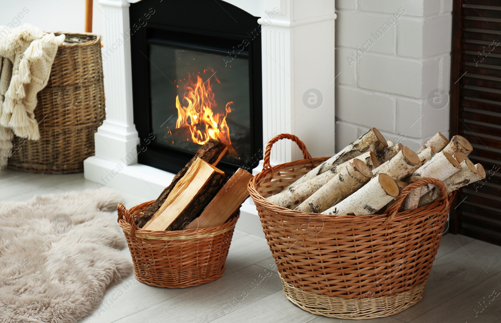 Photo of Firewood in wicker baskets near fireplace indoors