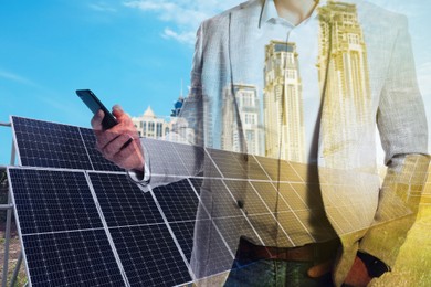 Image of Double exposure of businessman with smartphone and solar panels installed outdoors. Alternative energy source