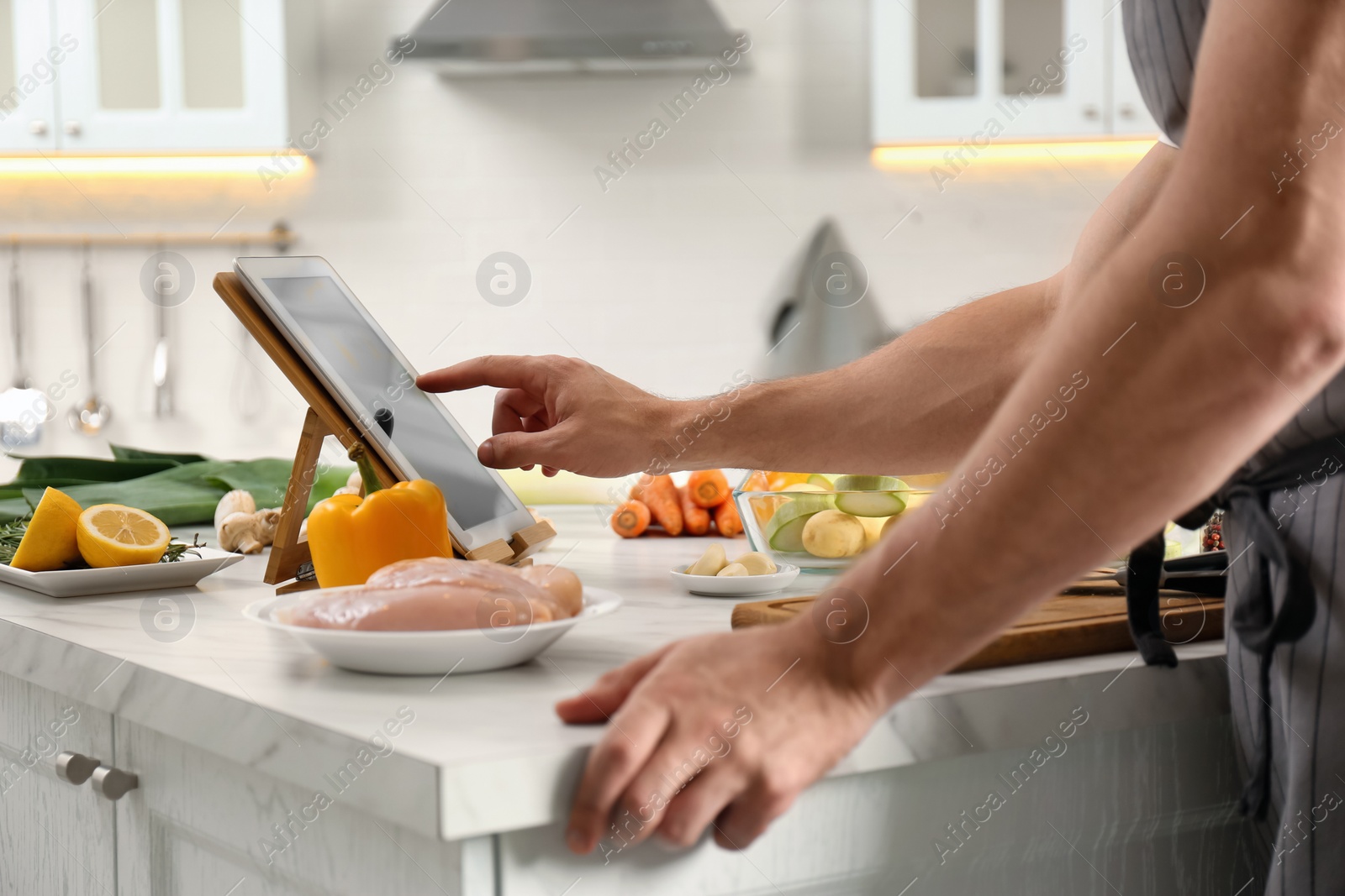 Photo of Man watching online cooking course via tablet in kitchen, closeup