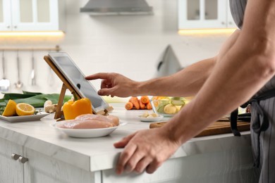 Photo of Man watching online cooking course via tablet in kitchen, closeup