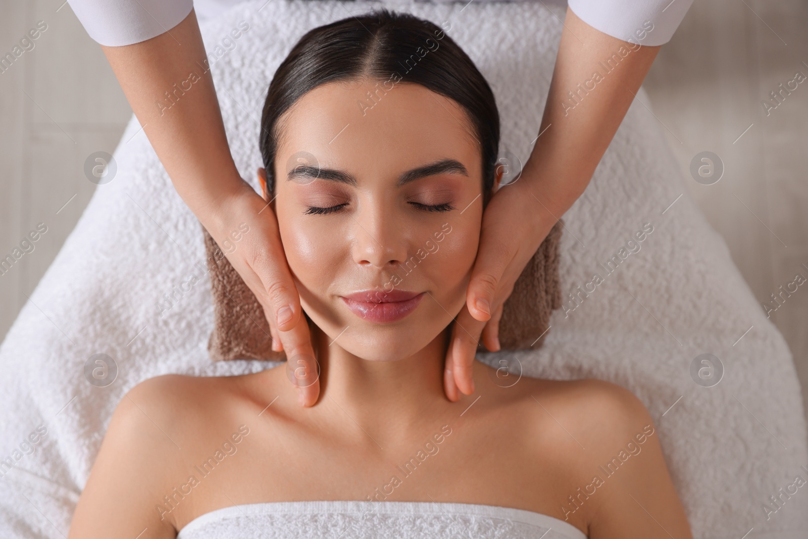 Photo of Young woman enjoying professional massage in spa salon, top view