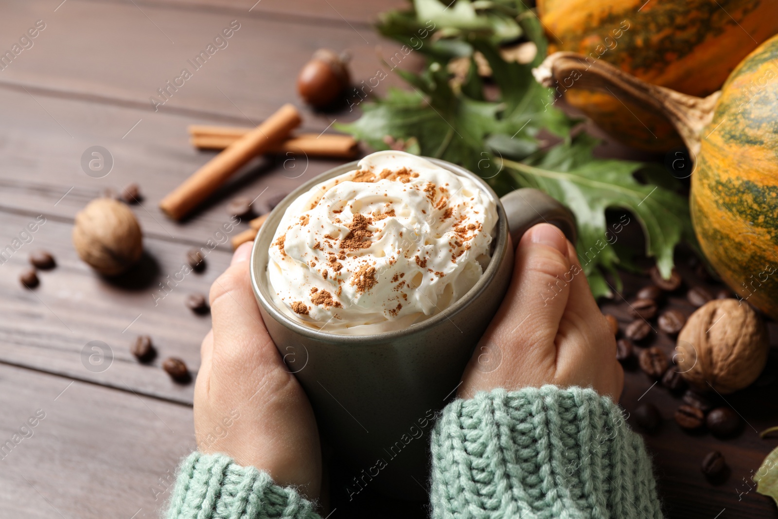 Photo of Woman with cup of tasty pumpkin spice latte at wooden table, closeup