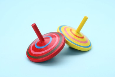 Photo of Two bright spinning top on light blue background. Toy whirligig