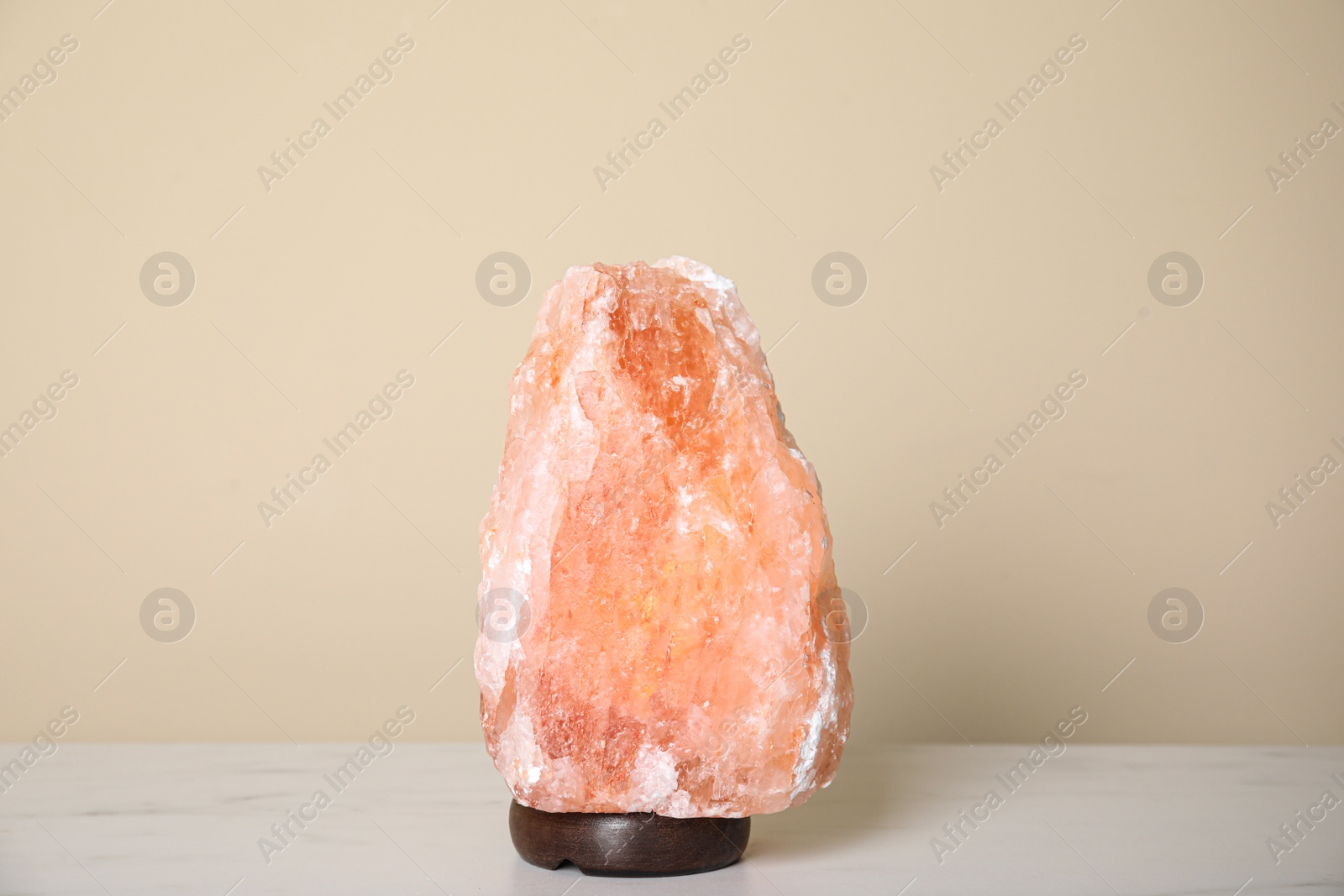 Photo of Himalayan salt lamp on table against beige wall