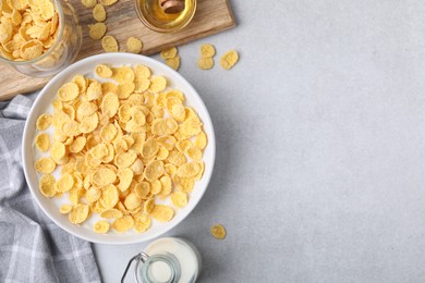 Photo of Breakfast cereal. Corn flakes and milk in bowl on light grey table, flat lay. Space for text