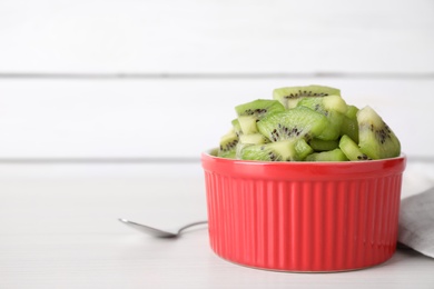 Photo of Bowl with kiwi slices on white table. Space for text