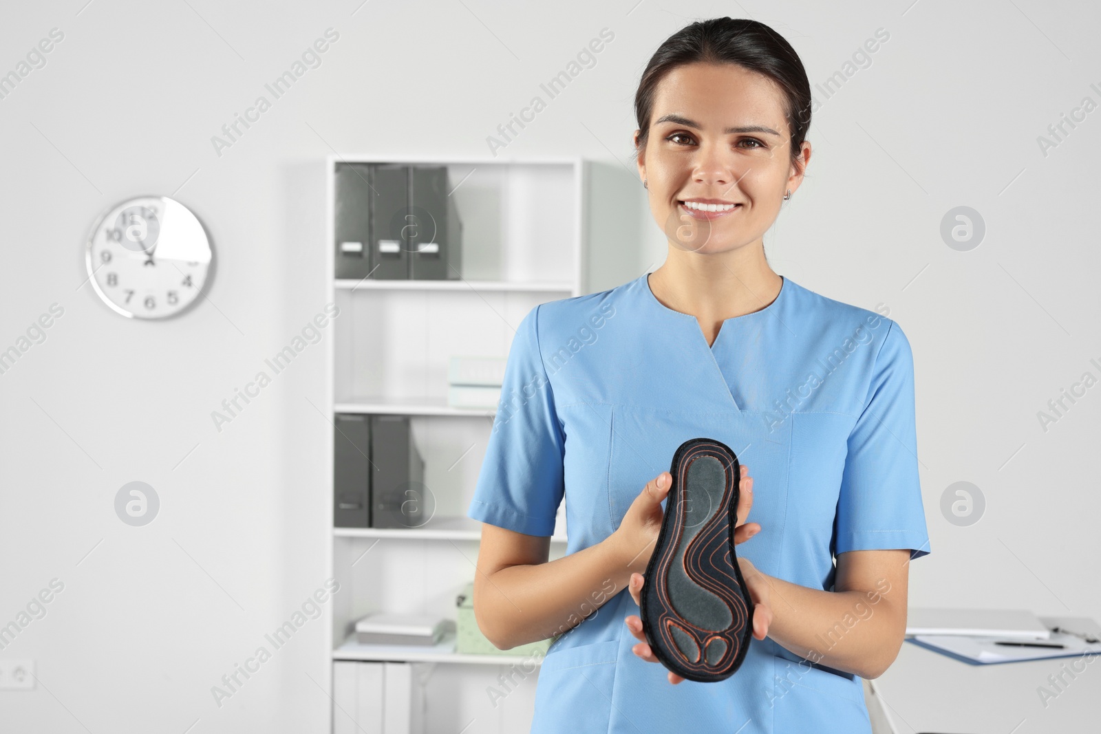 Photo of Beautiful female orthopedist showing insole in hospital