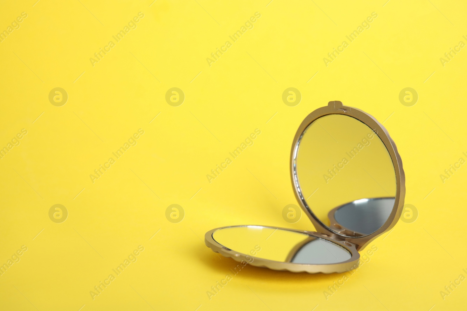 Photo of Stylish cosmetic pocket mirror on yellow background, space for text