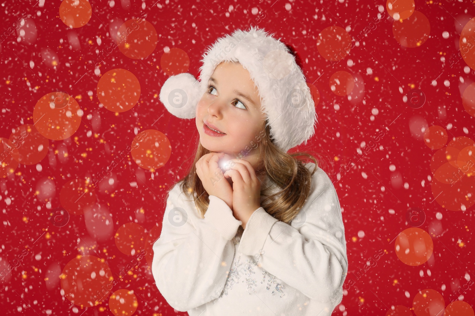 Image of Cute child in Santa hat on red background. Christmas celebration
