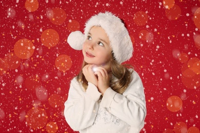 Cute child in Santa hat on red background. Christmas celebration