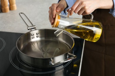 Photo of Vegetable fats. Woman pouring cooking oil into frying pan on stove, closeup