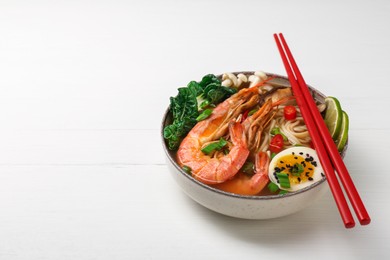 Photo of Delicious ramen with shrimps, egg and chopsticks on white wooden table, space for text. Noodle soup