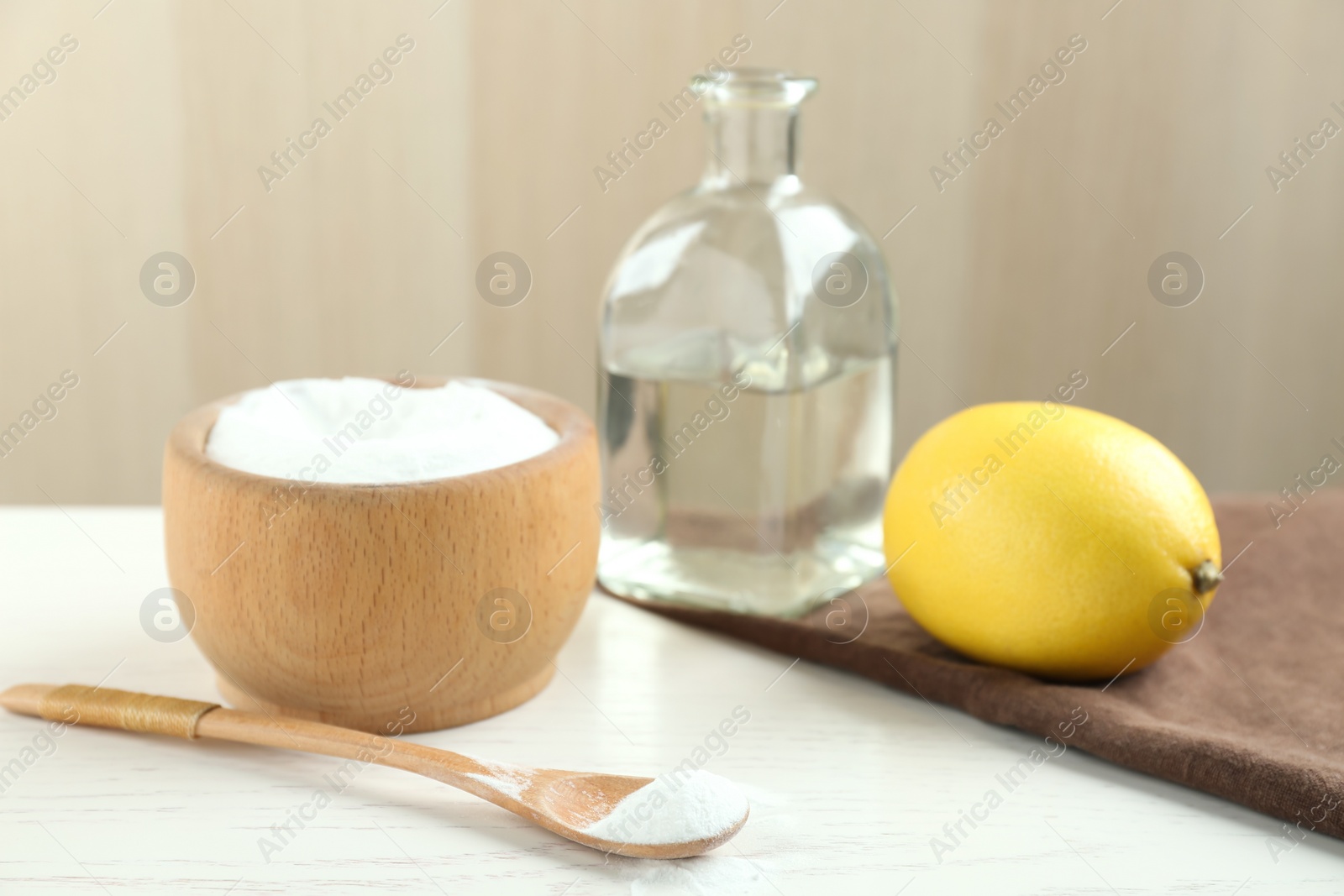 Photo of Baking soda, cut lemon and vinegar on white wooden table