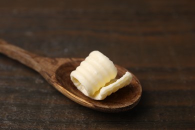 Photo of Tasty butter curl and spoon on wooden table, closeup