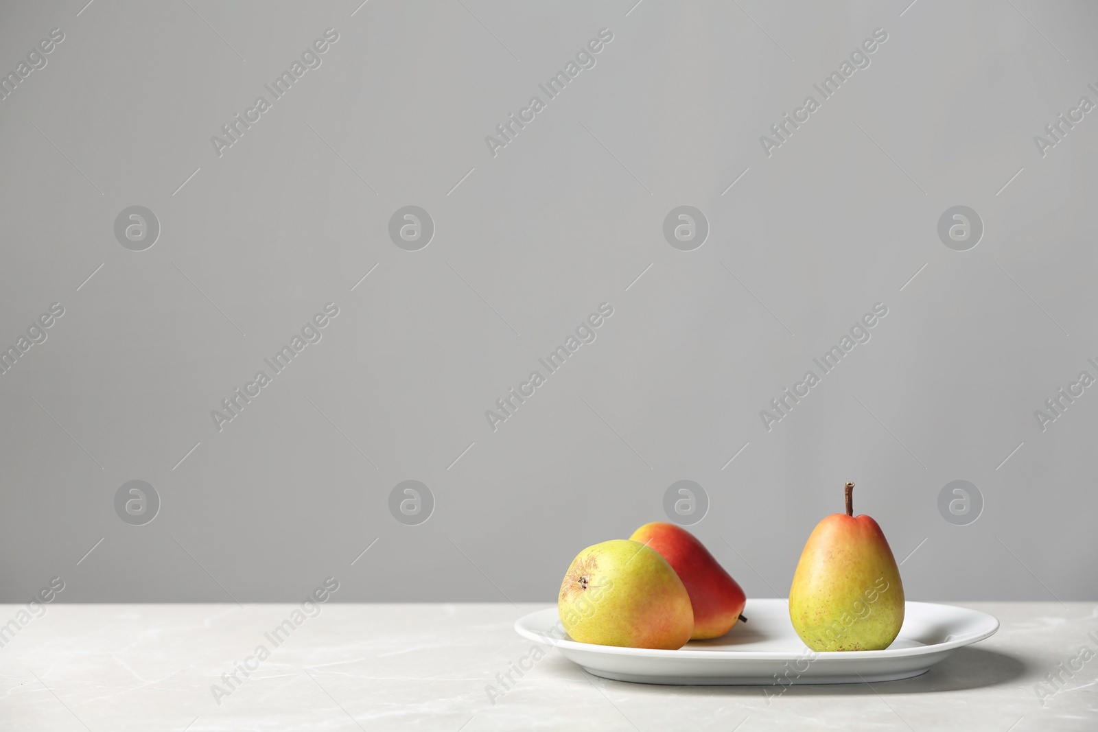 Photo of Plate with pears on table against grey background. Space for text