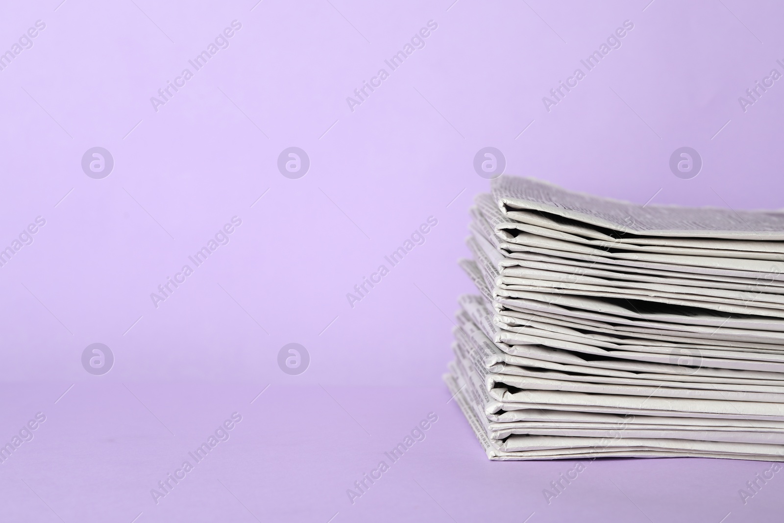 Photo of Stack of newspapers on light violet background, space for text. Journalist's work