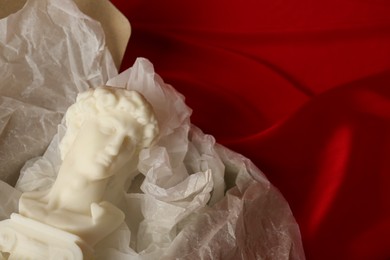 Photo of David bust candle on red fabric, space for text