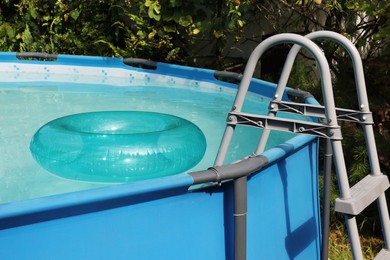 Photo of Inflatable ring floating on water in above ground swimming pool outdoors