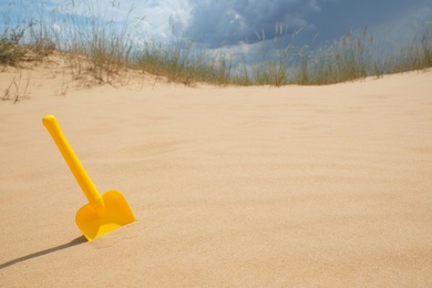 Yellow plastic shovel in desert on sunny day. Space for text