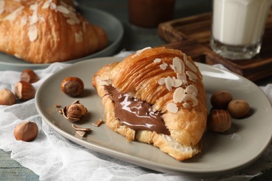 Delicious croissant with chocolate and nuts on table, closeup