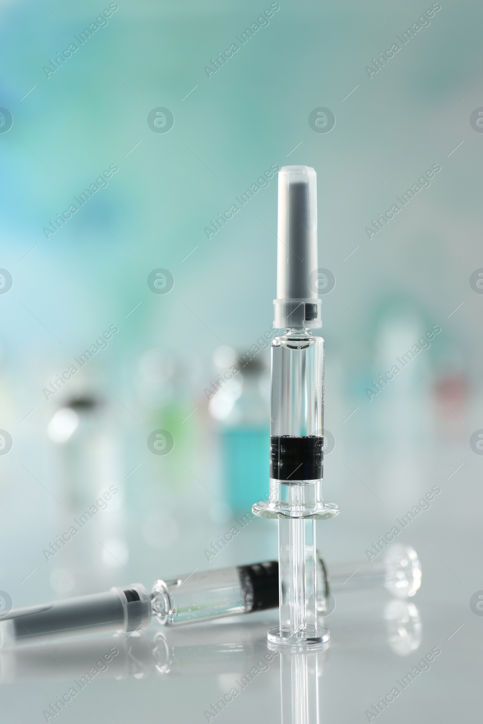 Photo of Syringes with COVID-19 vaccine on white table