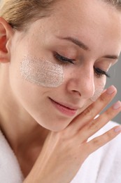 Woman with cosmetic product on her face, closeup. Spa treatments