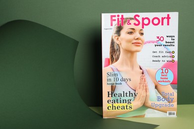 Modern printed sports magazine on green background, space for text