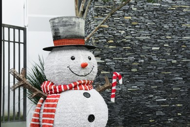 Photo of Funny snowman near house. Festive outdoor Christmas decoration