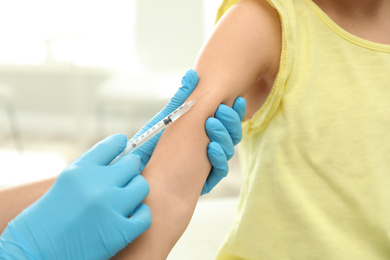 Photo of Doctor vaccinating little child in clinic, closeup