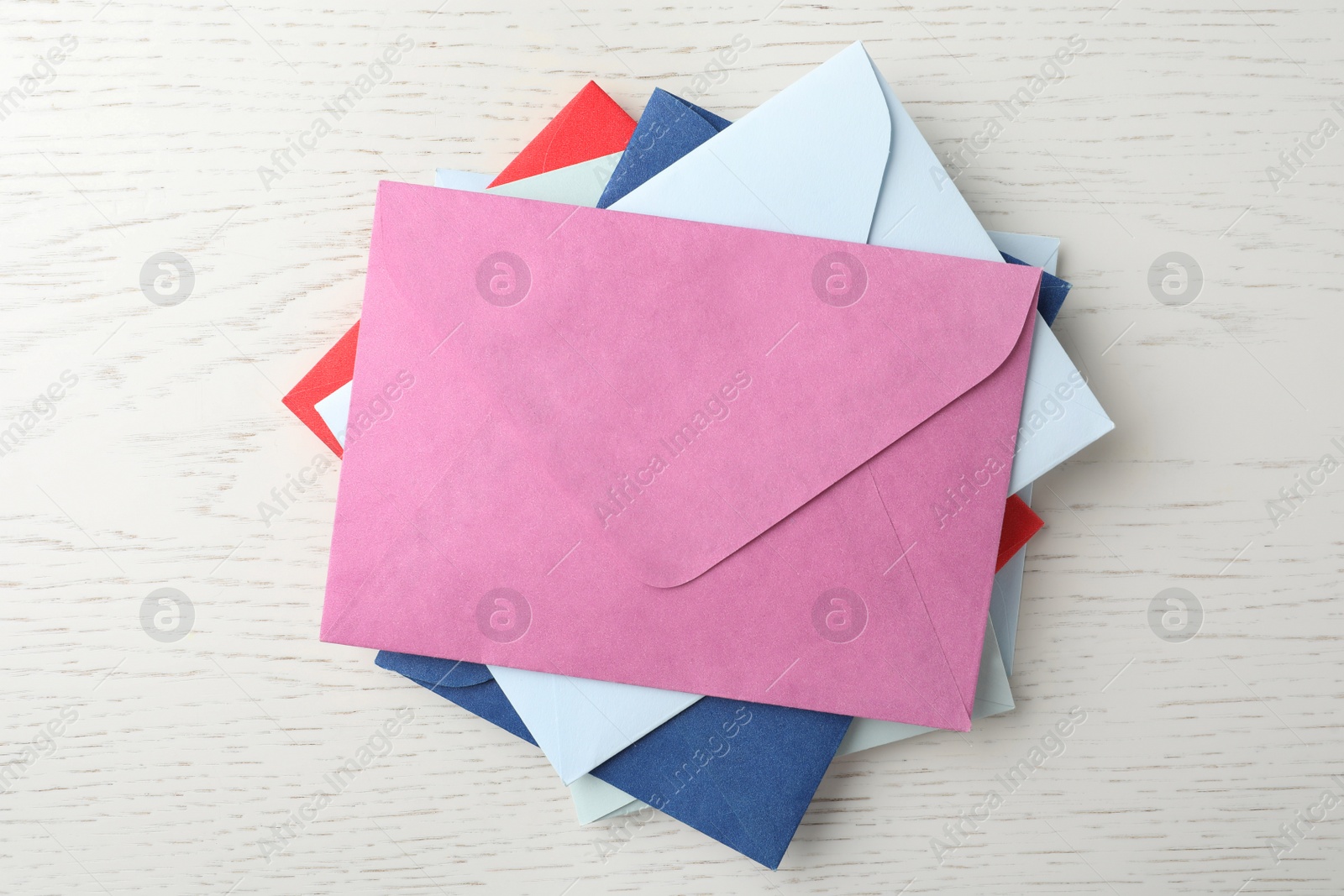 Photo of Colorful paper envelopes on white wooden background, top view