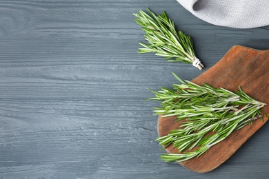 Photo of Fresh green rosemary on blue wooden background, flat lay. Space for text