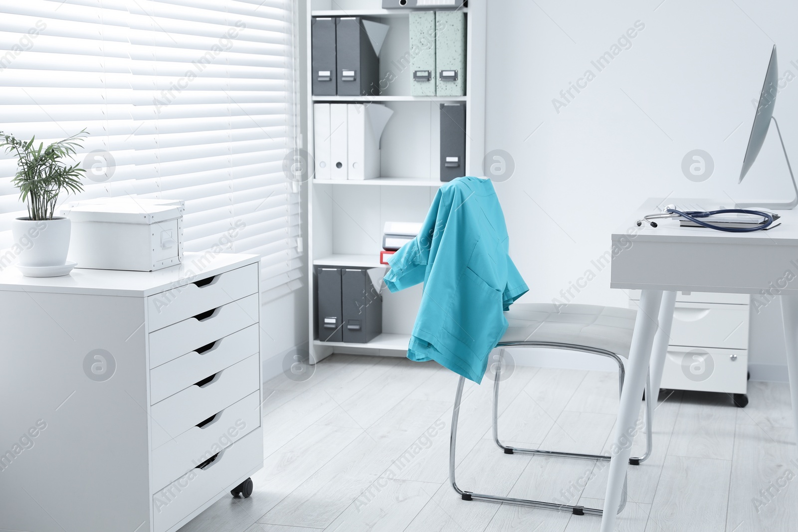 Photo of Turquoise medical uniform hanging on chair in clinic