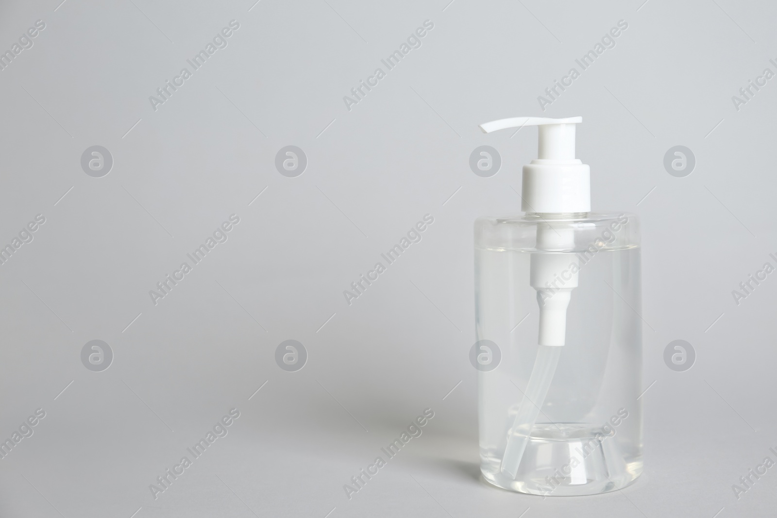 Photo of Dispenser bottle with antiseptic gel on light grey background. Space for text