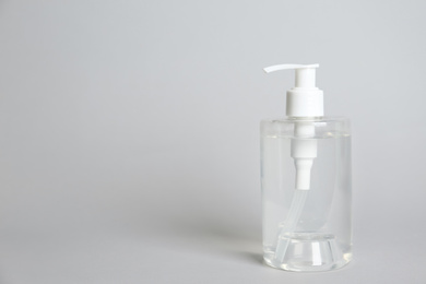 Photo of Dispenser bottle with antiseptic gel on light grey background. Space for text