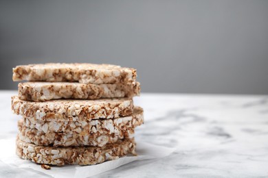 Photo of Stack of crunchy buckwheat cakes on white marble table, closeup. Space for text