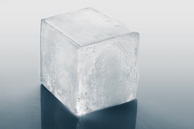 Crystal clear ice cube on light grey background