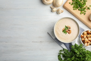 Flat lay composition with bowl of fresh homemade mushroom soup and space for text on wooden background