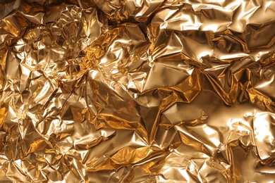 Photo of Crumpled golden foil as background, closeup view