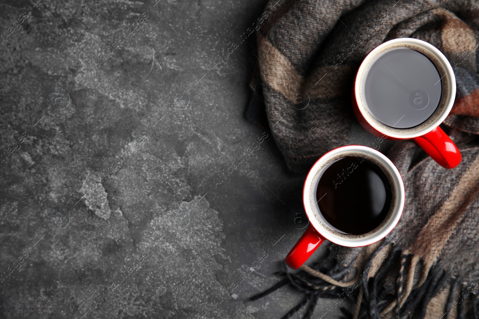 Photo of Flat lay composition cups of hot coffee and blanket on grey stone background, space for text. Winter drink